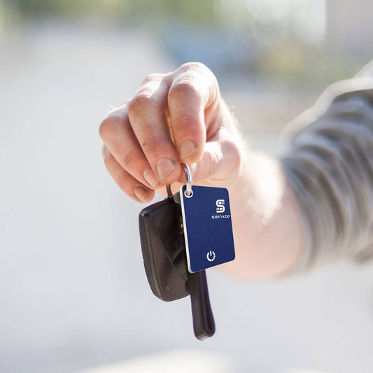 A-man's-hand-is-holding-a-car-key-with-a-Seinxon-locator-tag