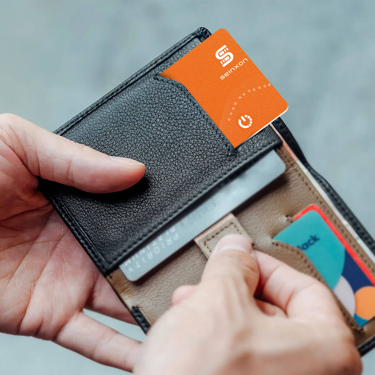 A-man's-hands-are-holding-a-wallet-with-a-Seinxon-wallet-tracker-card